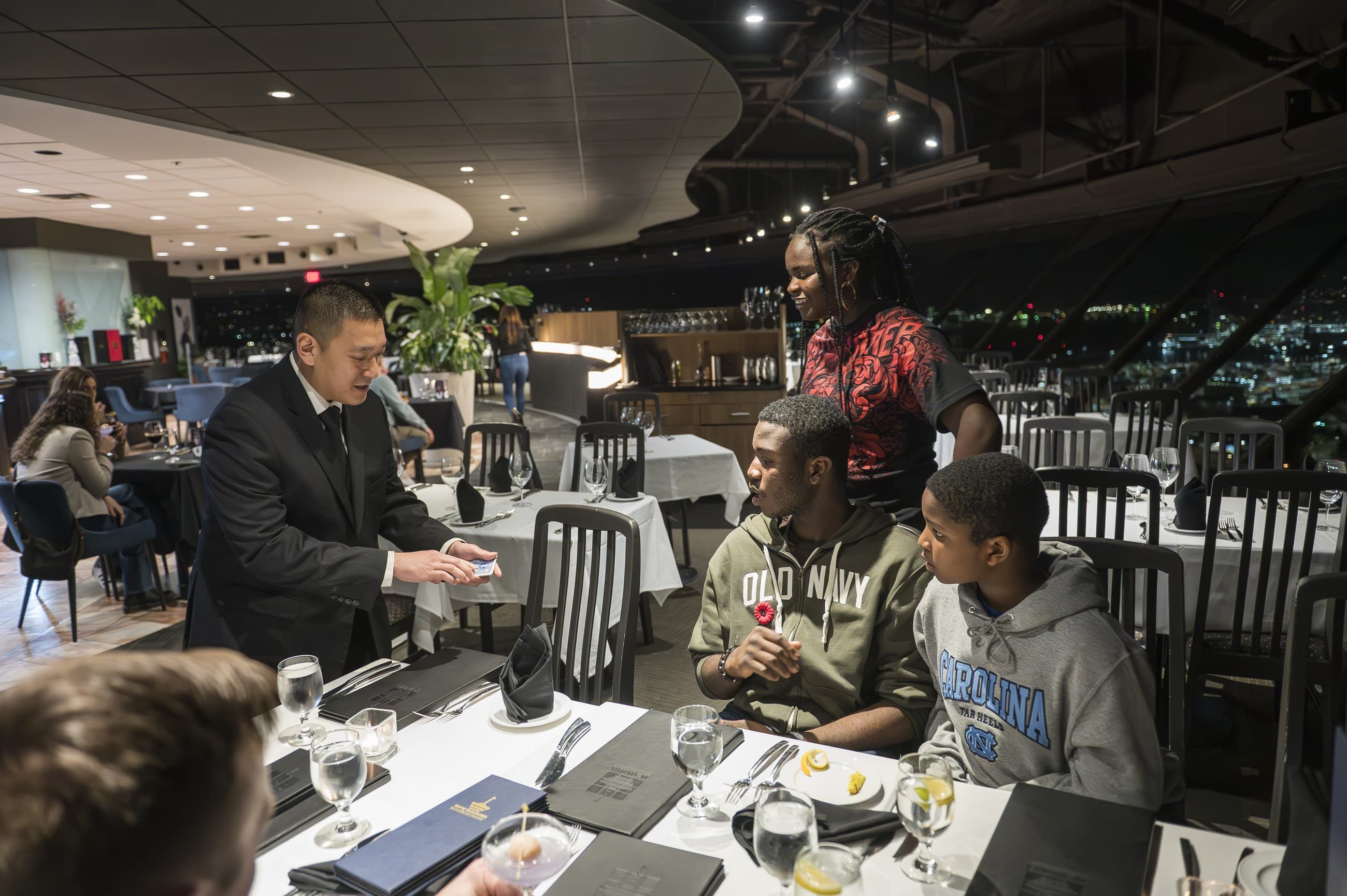 John Ha performing close-up magic at a table with Ontario event guests reacting in a conference-style setting